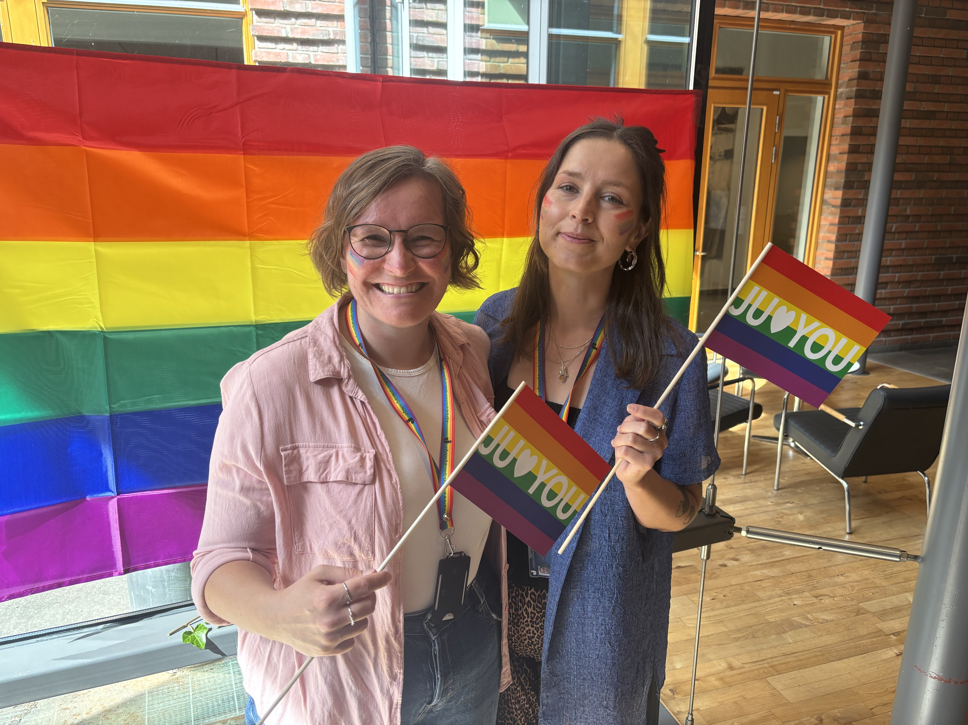 Två glada kvinnor med Prideflaggor