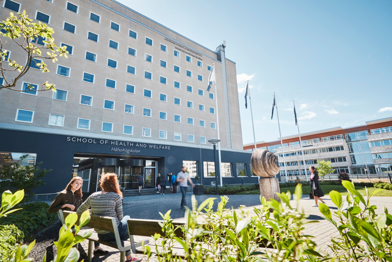 En grupp människor som sitter på en bänk framför en byggnad.
